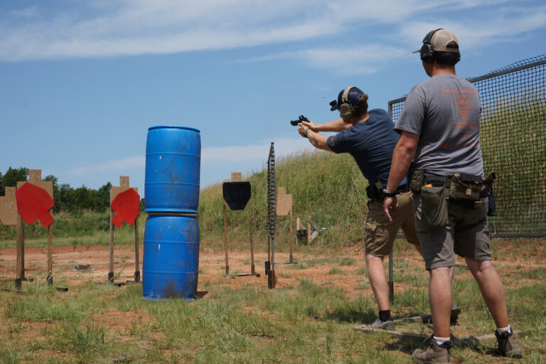 A competitor shoots at cardboard targets across open ground during the PCSL pistol match.