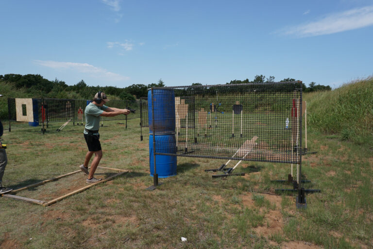 A competitor moves between wooden barricades on a PCSL pistol match stage.