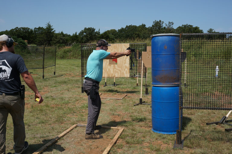 A competitor shoots past a wooden barricade during the PCSL pistol match.