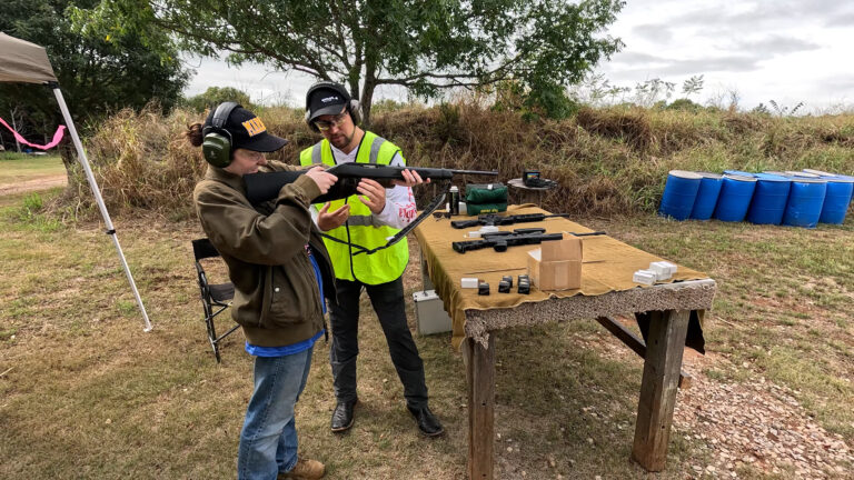 A club instructor explains rifle handling to a participant at the range.